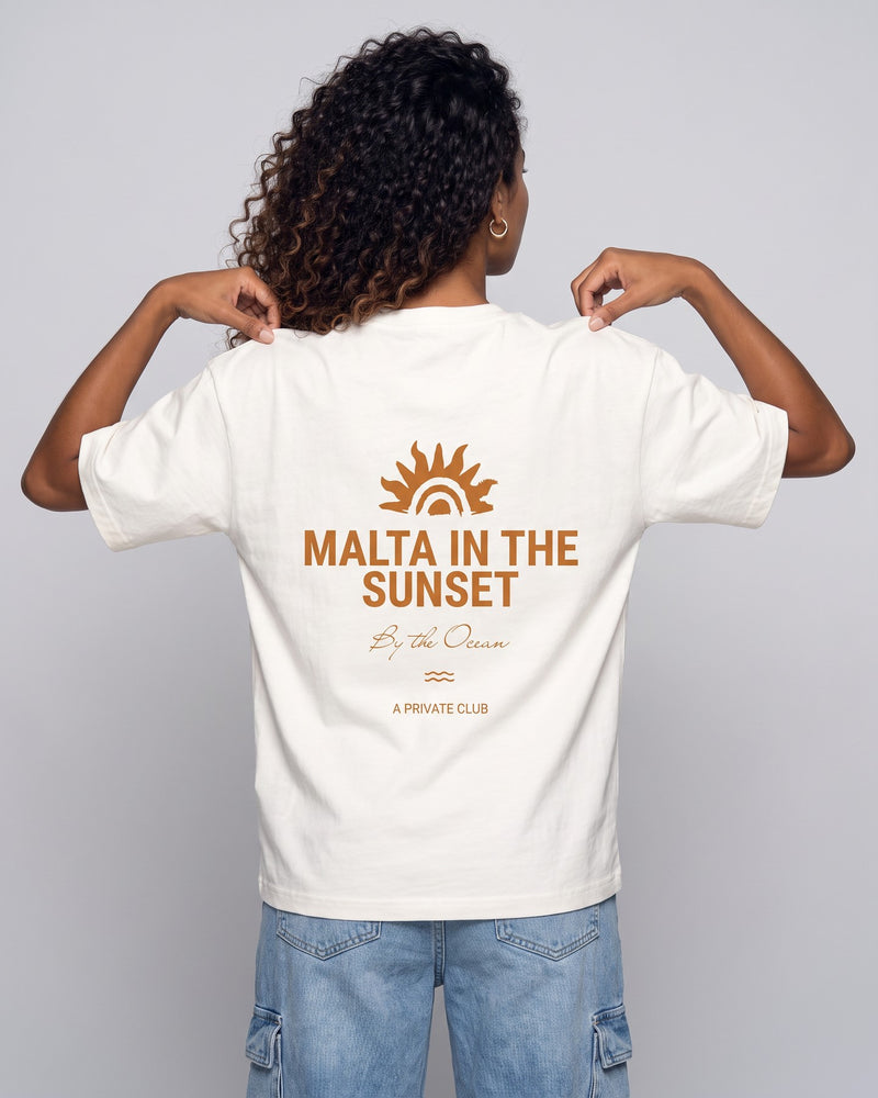 Camiseta oversized feminina MALTA® innerbloom off-white vista de costas no estúdio, com a frase “malta in the sunset”