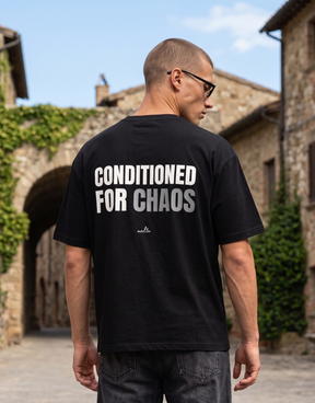 Camiseta oversized MALTA® Conditioned for Chaos preta usada ao ar livre, vista de costas