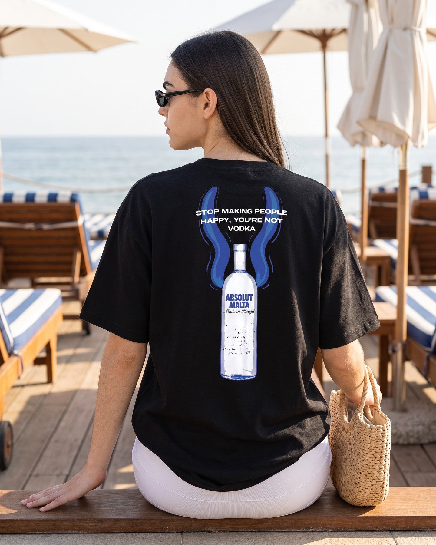 Mulher de costas usando a camiseta oversized MALTA® absolut malta preta num beach club