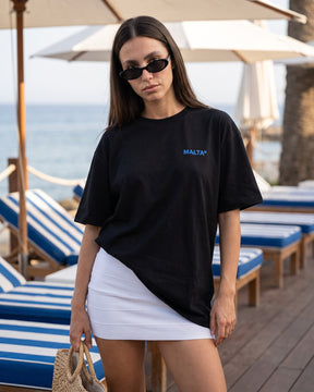 Mulher usando a camiseta oversized MALTA® absolut malta preta num beach club