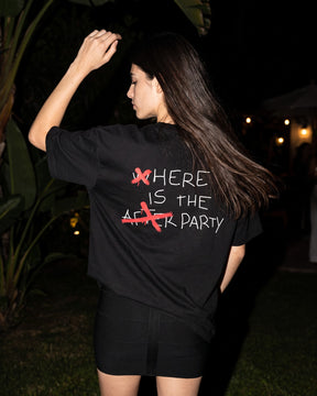 Mulher de costas usando a camiseta oversized MALTA® after party preta num terraço à noite