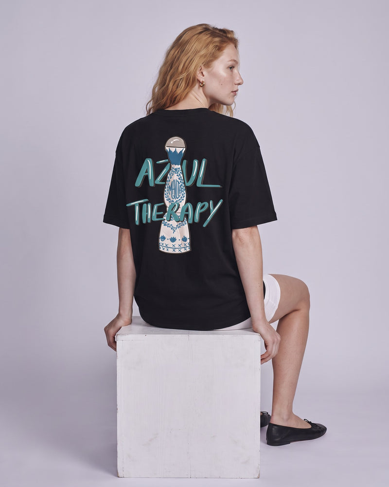 Camiseta oversized feminina MALTA® azul therapy preta vista de costas no estúdio, com a frase “azul therapy”