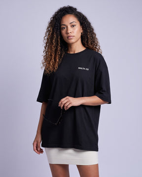 Camiseta oversized feminina MALTA® bad choices preta vestida de frente, no estúdio