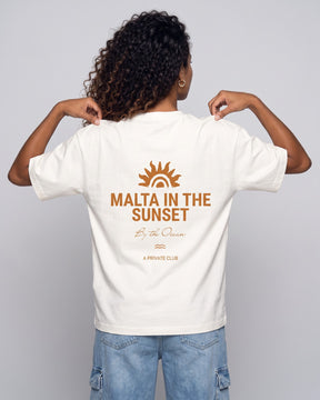 Camiseta oversized feminina MALTA® innerbloom off-white vista de costas no estúdio, com a frase “malta in the sunset”