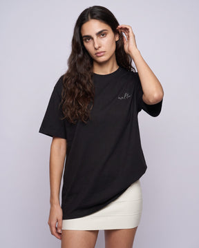 Camiseta oversized feminina MALTA® conditioned for chaos preta vestida de frente, no estúdio