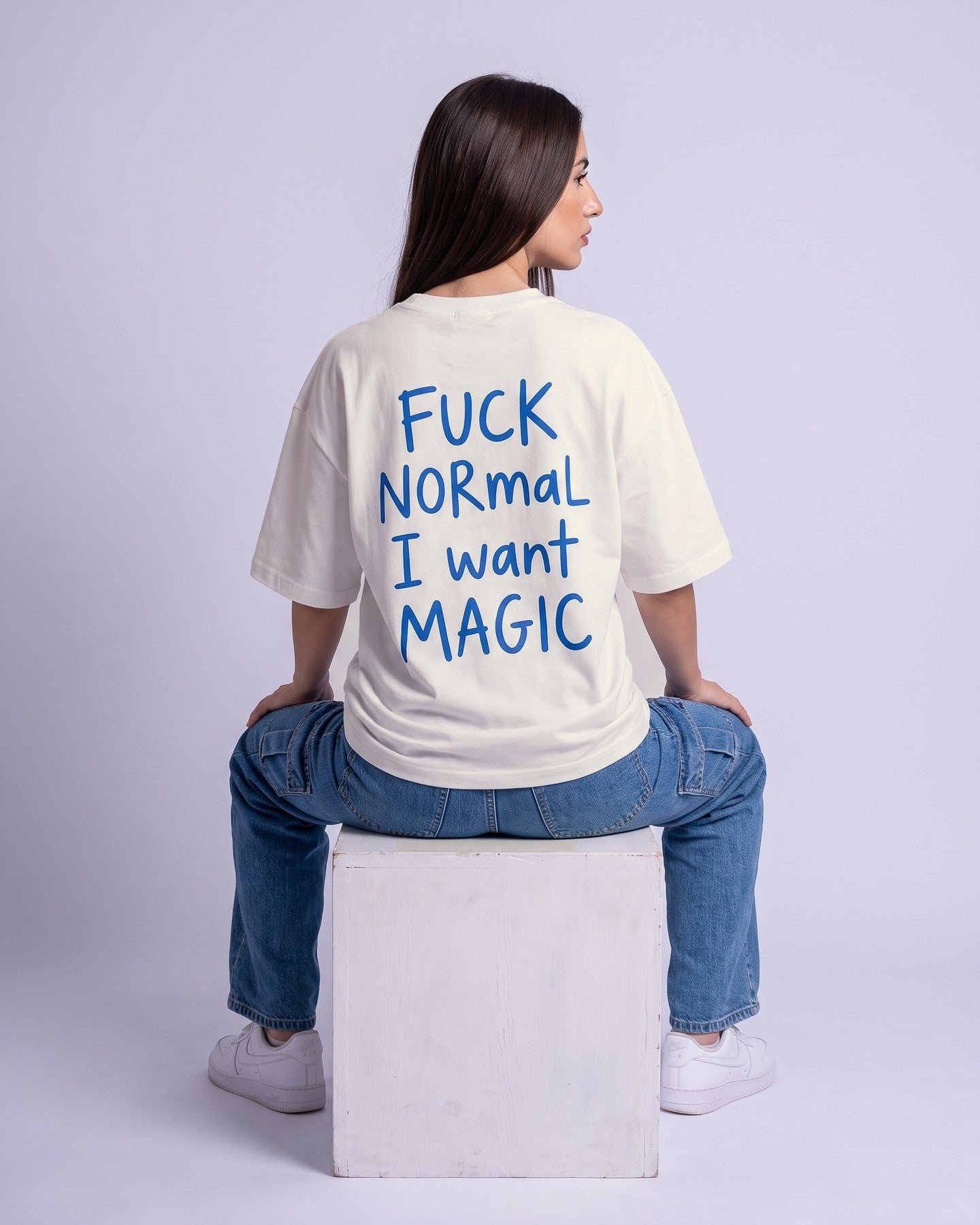 Camiseta oversized feminina MALTA® i want magic off-white vista de costas no estúdio, com a frase “fuck normal, i want magic”