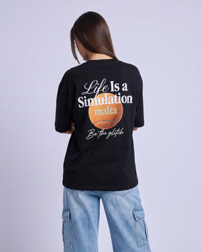 Camiseta oversized feminina MALTA® life is a simulation preta vista de costas no estúdio, com a frase “life is a simulation”