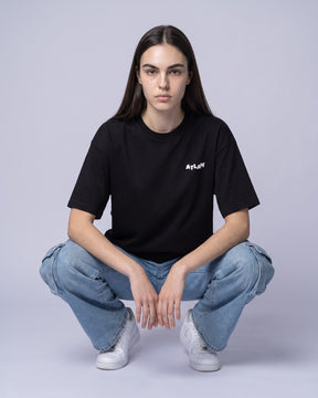 Camiseta oversized feminina MALTA® life is a simulation preta vestida de frente, no estúdio