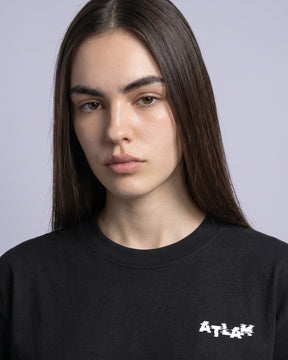 Detalhe da camiseta oversized MALTA® life is a simulation preta no corpo feminino