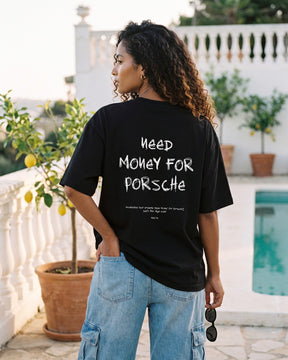 Mulher de costas usando a camiseta oversized MALTA® need money for porsche preta no terraço de um clube na Riviera