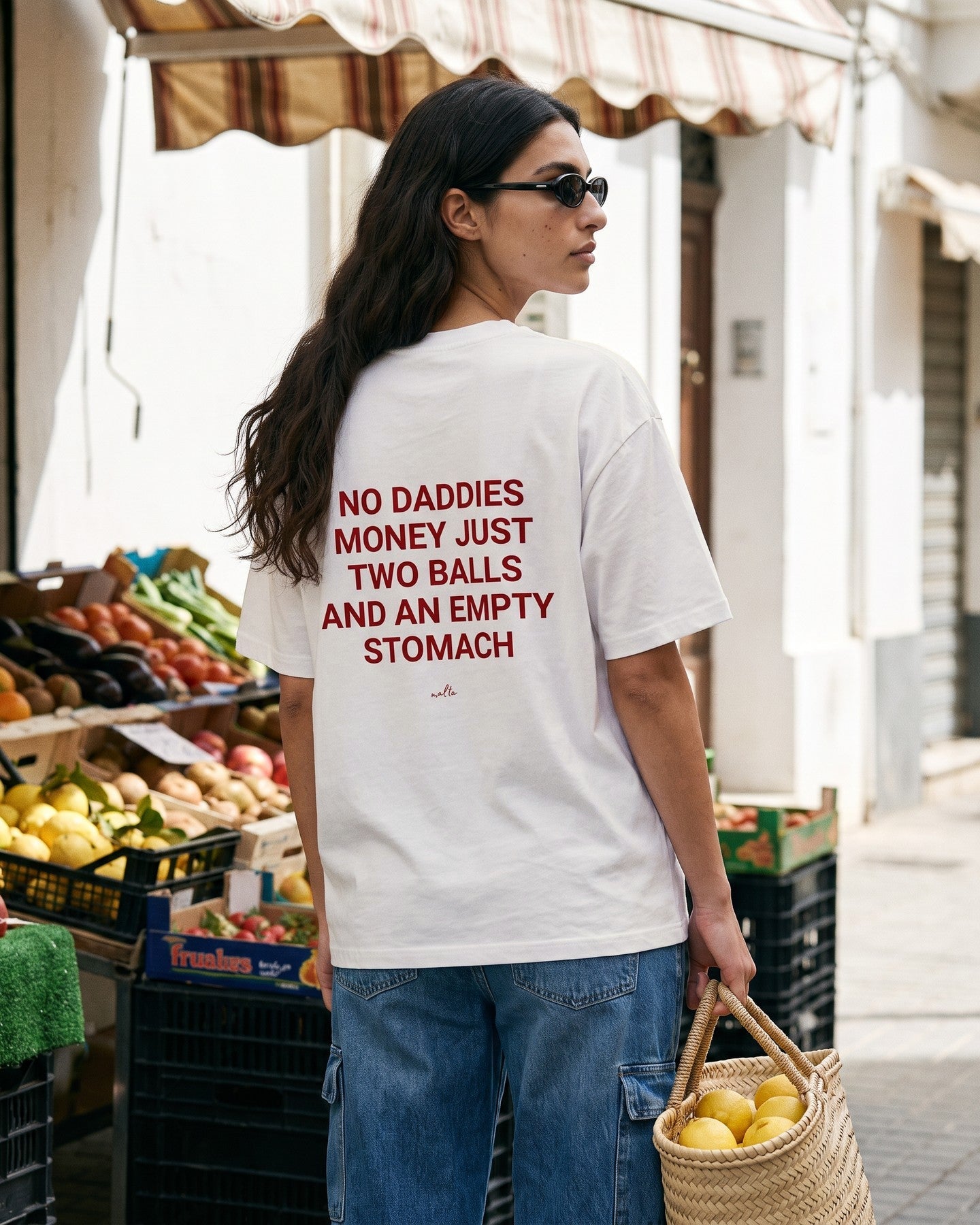 Mulher de costas usando a camiseta oversized MALTA® no daddies money off-white numa feira de rua