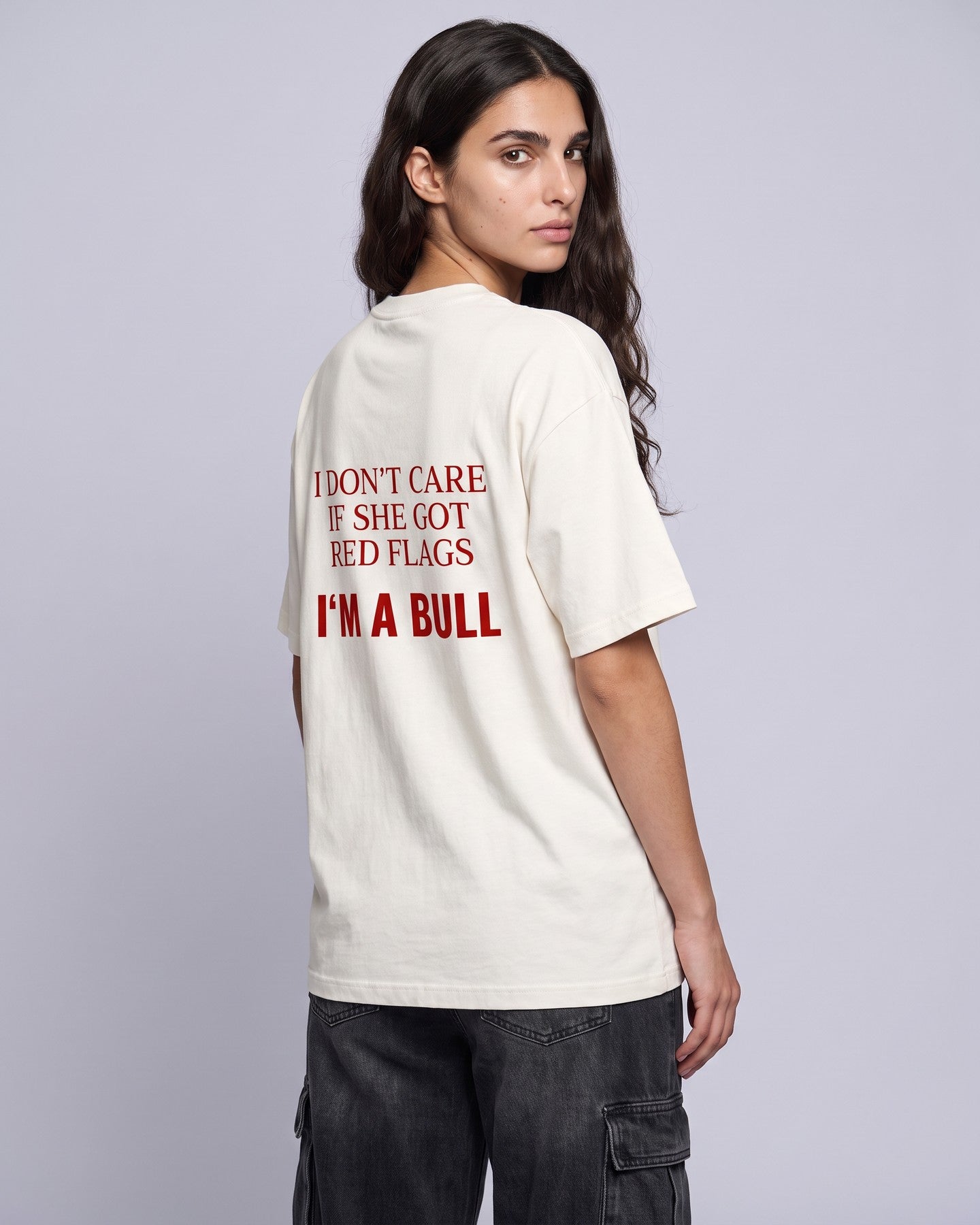 Camiseta oversized feminina MALTA® red flags off-white vista de costas no estúdio, com a frase “i don't care if she got red flags, i'm a bull”
