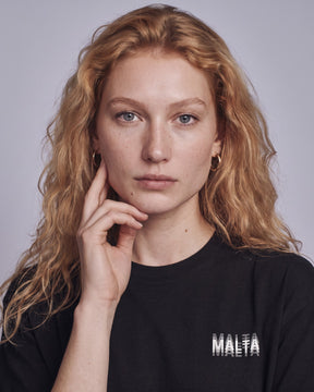 Detalhe da camiseta oversized MALTA® you might be drunk preta no corpo feminino